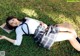 A woman in a school uniform laying on the grass.