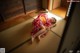 A woman in a red kimono laying on the floor.