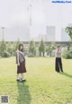 A couple of women standing on top of a lush green field.