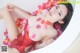 A woman in a red bathing suit laying in a bathtub with rose petals.