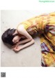 A woman laying on the ground in a yellow dress.