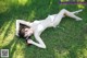 A woman in a white bikini laying on the grass.