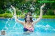 A woman in a bikini splashing water in a swimming pool.