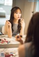 A woman applying lipstick in front of a mirror.