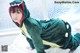 A woman in a green dinosaur costume laying on a bed.