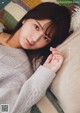 A woman laying on top of a couch next to a pillow.