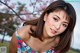 A beautiful young woman posing in front of a flowering tree.