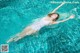 A woman floating in a swimming pool with her arms outstretched.