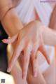 A woman in a white dress is touching her hands.