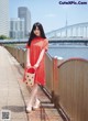 A woman in a red dress standing on a bridge.