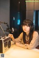 A woman sitting at a table in front of a microphone.