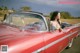 A woman sitting in the driver's seat of a red convertible car.