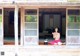 A woman sitting on the porch of a house holding a cup of tea.