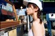 A woman in a white hat standing in front of a food stand.